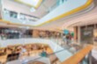 Abstract bokeh background of a shopping mall with blurred people walking on a ramp.
