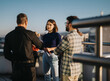 © qunica.com - Business colleagues engage in a brainstorming session on a rooftop balcony at sunset, embracing diversity and creativity in a relaxed atmosphere. The multicultural team discusses innovative ideas
