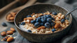 © Jhati - Close up of a bowl of granola with blueberries and almonds on a gray surface near spoon