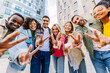 © Xavier Lorenzo - Group of cheerful multi-ethnic students gesturing peace sign with fingers while standing together in the city