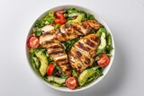 Grilled chicken salad with avocado and tomatoes in a white bowl on a light background, top view, flat lay. Healthy food idea. Concept for healthy eating, weight loss, or body-building advertising