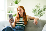 Portrait beautiful smiling young woman at home on sofa using cellphone