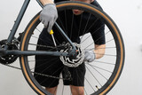 A person is skillfully repairing a bicycle's disc brake in a well-lit bike shop. ensuring a safe and efficient fix for riders.