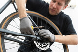 A person is skillfully repairing a bicycle's disc brake in a well-lit bike shop. ensuring a safe and efficient fix for riders.