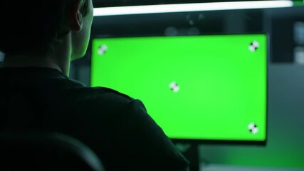 Person Working on Computer with Green Screen Display