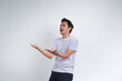 © Rangga Ispraditya - A young man in a white t-shirt expressing confusion or questioning with open hands gesture. Studio shot on plain background showing human emotion.