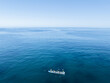 © AmazingAerialAgency - Aerial view of a rowing boat gliding across the glassy, turquoise waters under a clear sky, the epitome of serenity., Perth, Western Australia, Australia.