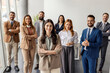 © Dusan Petkovic - Smiling female executive standing at corporation with her leadership team in a blurry background.