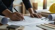 © detiyy - Architect reviewing building plans with pencil