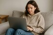 © Татьяна Евдокимова - Freelancer working on laptop sitting comfortably on couch at home, enjoying flexible work arrangement
