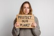 © PirisaTK - A woman holds a cardboard sign reading 'Protect Our Planet,' advocating for environmental awareness and sustainability.