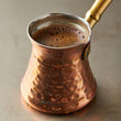 © MD - Close up of turkish coffee in a hammered copper cezve with a golden handle on a neutral surface
