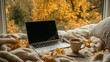 © Ksu_Sha - Cozy autumn scene with laptop coffee and blanket near window decorated with golden fall leaves