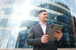© muse studio - Business professional engages with tablet outside modern glass building in vibrant city atmosphere