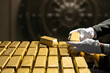 © TSViPhoto - Banker's hands in white gloves, bank vault manager holding a gold bar, national gold reserv holdings concept. Savings and investments, business and finance