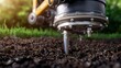 © medi - Close-up of a soil sampling machine extracting a core sample from the earth in a field with green grass.