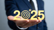 © DreamyDesignsCo - Ambitious business leader holds golden 2025 with target symbol, planning future success