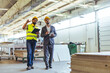 © Dragana Gordic - Two Engineers Discussing in a Factory Warehouse Wearing Hard Hats and Safety Gear