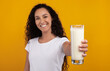 © Prostock-studio - Portrait of beautiful young woman holding glass of milk, lady showing and offering fresh diary product close up to camera. Millennial female recommending healthy nutrition, selective focus on hand
