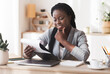 © Prostock-studio - Paperwork. Pensive african american businesswoman checking financial reports at workplace in office, satisfied by result of her company