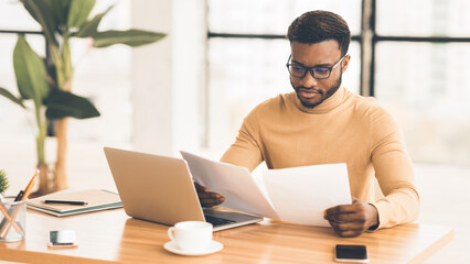 Concentrated Black Businessman Checking Financial Reports In Modern Office. Panorama, copy space