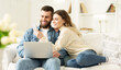 © Prostock-studio - Surfing Internet. Young Couple Relaxing With Laptop And Smartphone, Sitting On Sofa