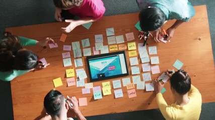 Top down view of programmer brainstorming and planning about web design while looking at tablet wireframe prototype. Aerial view of skilled developer team talking about digital application. Symposium.
