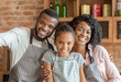 © Prostock-studio - Happy african family taking selfie at kitchen, wearing aprons and smiling at camera