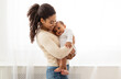 © Prostock-studio - Loving African American Mother Holding Baby Cuddling Toddler In Arms Enjoying Motherhood And Child Care Standing Indoors. Happy Motherhood Moments, Mom And Infant's Bond Concept