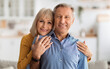 © Prostock-studio - Happy Marriage. Senior Wife Embracing Her Husband Posing Together Holding Hands Smiling Looking At Camera Standing In Kitchen At Home. Retirement Lifestyle Concept