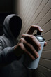 © Sunshine Design - Anonymous hooded man holding spray can in dramatic lighting against brick wall