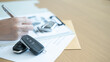 © Jokiewalker - Car remote keys and pen with contract papers showing the process of auto sales deal paperwork and business transaction