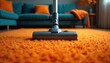 © Vadym - Close-up of vacuum cleaner head on vibrant orange carpet in modern living room. Teal sofa with orange cushions visible. Efficient cleaning action for a tidy, dust-free home environment.