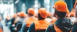 © Cheewynn - A group of construction workers in orange safety helmets and vests attend a meeting or training session indoors