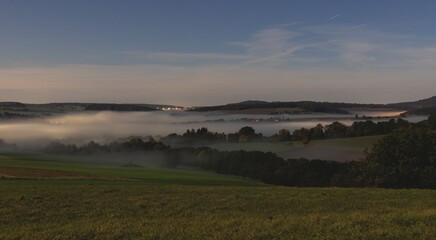 Wall Mural - Misty Valley at Dusk with Distant City Lights