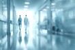 © Golden - Abstract blurred image of a hospital corridor with two figures in lab coats walking towards a bright light at the end. Focus on the depth of field effect