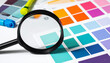 © Gunawan - Detailed inspection of a vibrant color swatch guide with a magnifying glass for creative project selection