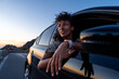 © Martí Rosselló - Young woman enjoys golden hour scenery from car window. Concept of freedom, sunset drive, peaceful escape.