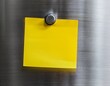 © Raymond - yellow sticky note attached to a metallic fridge with a magnet background shows kitchen appliance blurred minimalist home note reminder