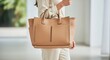 © MindRender - Woman carrying a stylish tan leather tote bag outdoors