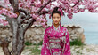 © hasara - Elegant woman wearing traditional pink kimono standing beside blooming cherry blossom tree, serene cultural portrait celebrating Japanese heritage, springtime beauty, and tradition in nature.