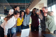 © CarlosBarquero - Multicultural colleagues gather in a tight huddle around a table, smiling and cheering after good news in a bright modern office, expressing unity, motivation and collaborative spirit.