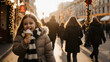 © Saranya - Happy girl eating ice cream on festive winter street, wearing warm coat and striped scarf, surrounded by people and holiday lights, enjoying cheerful outdoor atmosphere