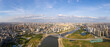 A vast cityscape shows buildings and a river under a bright sky.