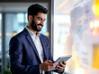 © Wang - A man in a blue suit, holding a tablet, is smiling and looking at a whiteboard in a well-lit office.