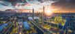 © zhao dongfang - Spectacular aerial view of a massive, illuminated oil refinery complex at sunrise with the sun bursting through dramatic clouds.