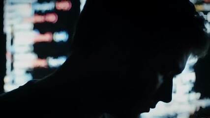 Silhouette of a person in front of a screen with code or data.