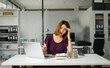 © NINENII - Asian woman stressed over credit card debt, holding bills in frustration.