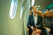 © Wanwajee - Modern Asian professional woman with dark complexion seated on plane, smartphone in hand, enjoying comfortable service. Best for aviation marketing, airline service, passenger experience.