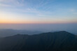 Jiugong Mountain offers vast scenic views. The mountain range stretches with layers of hills disappearing into the distance under a soft sky gradient.